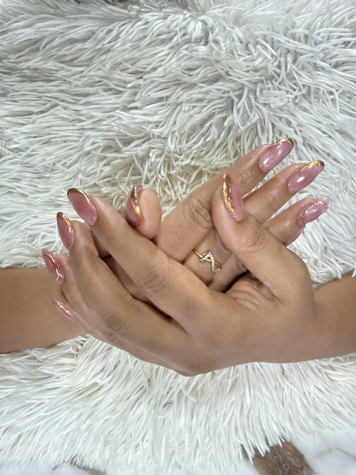 Pink nails with gold detailing, photographed against a white background